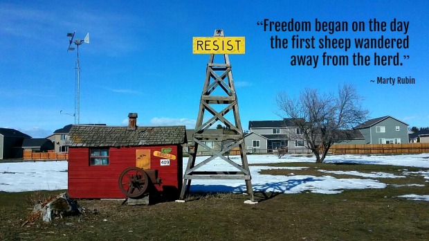 old windmill sign that says resist in a field